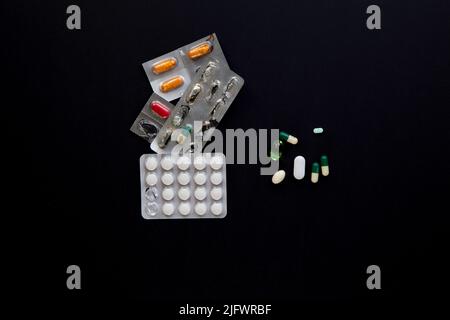 blister packs and medicial pills scattered on a black table Stock Photo