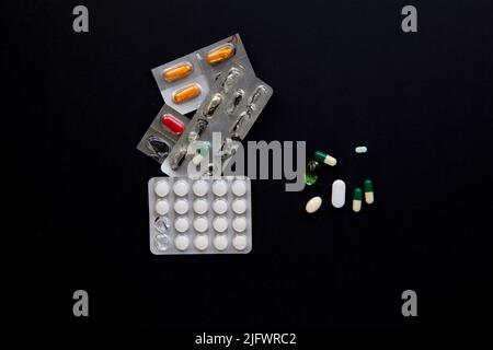 blister packs and medicial pills scattered on a black table Stock Photo