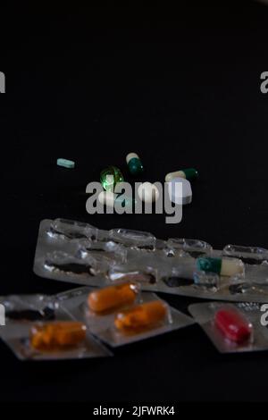 blister packs and medicial pills scattered on a black table Stock Photo