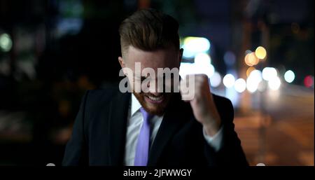Happy business man walking at night in city celebrating success raising fist cheering Stock Photo