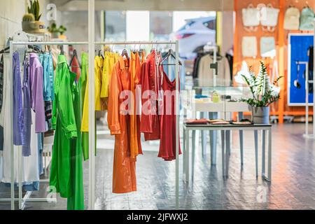 Bright multicolored youth clothes on hangers in shop, summer and spring assortment, clothing store Stock Photo