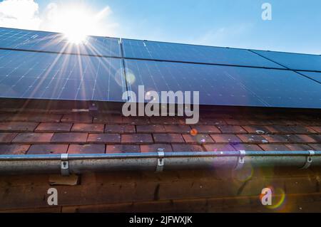 Sun rays shine on roof with solar panels. Renewable energy concept. Stock Photo