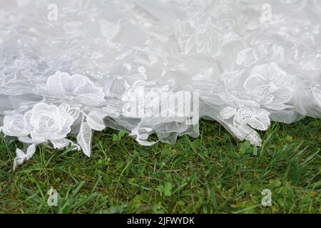 Close-up of a train of a wedding dress on a green turf Stock Photo