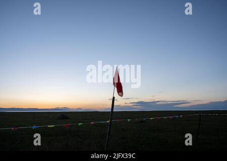A border on the beach separated by different colored flags a large red flag planted in the middle Stock Photo