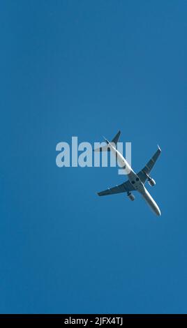 Warsaw, Poland - June 26, 2022: Passenger line airplane over blue sky, view from the ground. Travel by plane. Stock Photo