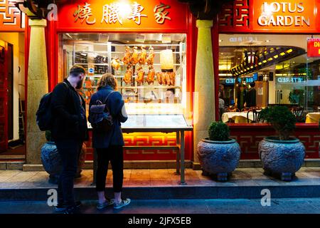 Showcase of a restaurant in Chinatown with crispy ducks hanging. Chinatown is an ethnic enclave in the City of Westminster. The enclave currently occu Stock Photo