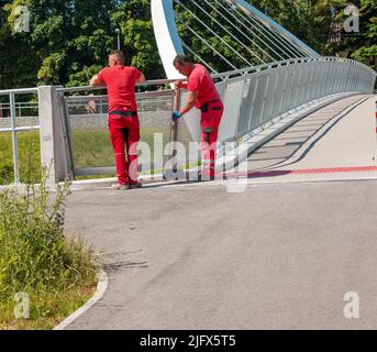 Nitra, Slovakia - 06.16.2022: Photo of two men cleaning the street with a broom and a shovel Stock Photo
