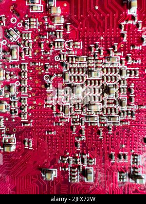 Close-up of transistors and microchips on the red circuit board Stock Photo