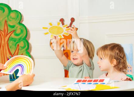 Boy in kindergarten development class show sun weather card Stock Photo