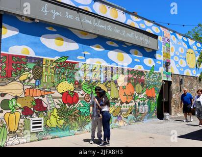 People passing a large wall with street art in Cleveland, Ohio in May 2022 Stock Photo