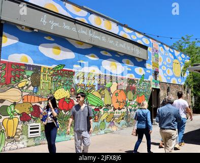 People passing a large wall with street art in Cleveland, Ohio in May 2022 Stock Photo