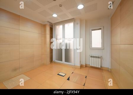 Empty room with technical floors in wood color and emergency door made of aluminum and glass Stock Photo