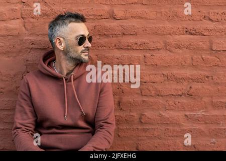 A handsome man leaning on a red brick wall Stock Photo