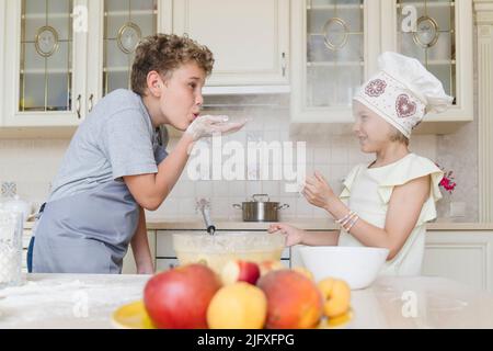 Brother and sister have fun playing with flour in the kitchen. Stock Photo