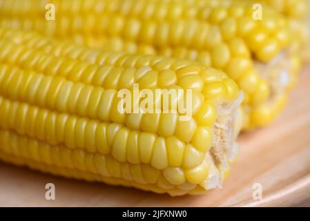 sweet corn cooked on wooden plate background, close up ripe corn cobs steamed or boiled sweetcorn for food vegan dinner or snack Stock Photo