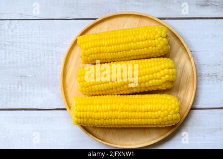 sweet corn cooked on wooden plate background, ripe corn cobs steamed or boiled sweetcorn for food vegan dinner or snack - top view Stock Photo