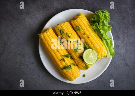 sweet corn food with salad vegetable lime coriander and lettuce, sweet corn cooked on white plate, ripe corn cobs steamed or boiled sweetcorn for food Stock Photo
