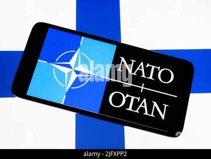 Ukraine. 05th July, 2022. In this photo illustration, NATO (North Atlantic Treaty Organization) logo is seen on a smartphone screen in front of Finland flag in the background. NATO Ambassadors signed the Accession Protocols for Finland and Sweden at NATO. Credit: SOPA Images Limited/Alamy Live News Stock Photo