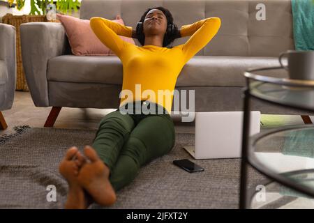 African american young female freelancer listening music on headphone while taking break from work Stock Photo