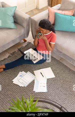 African american young female freelancer drinking coffee while working in living room at home Stock Photo
