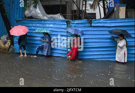 Mumbai, India. 05th July, 2022. Women holding umbrellas are seen crossing a flooded street amidst heavy rain in Mumbai. Mumbai witnessed heavy rain due to which streets were water logged in low lying areas and traffic was slow moving across the city. Indian Meteorological Department (IMD) has predicted moderate to heavy rain in the next 24 hours in the city. Credit: SOPA Images Limited/Alamy Live News Stock Photo