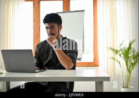 Smart intelligent asian businessman, male office worker or engineer working in the office, using laptop computer. Stock Photo