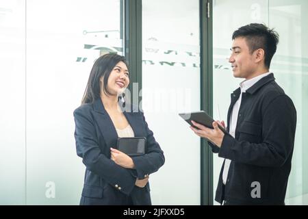 Business people holding digital tablet and talking to each other. Workplace setting. Stock Photo