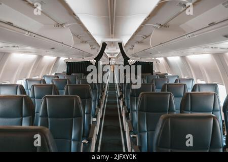 Commercial aircraft cabin with rows of seats down the aisle Stock Photo