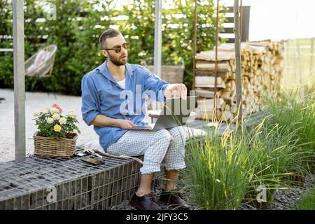Man works on laptop while sitting at backyard Stock Photo