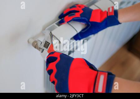 Male plumber installing heating radiator in house Stock Photo