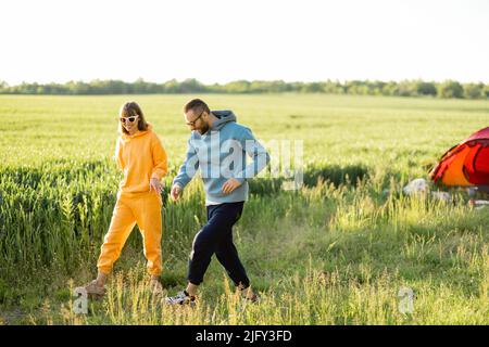 Young couple spend summer time at campsite on a green field Stock Photo