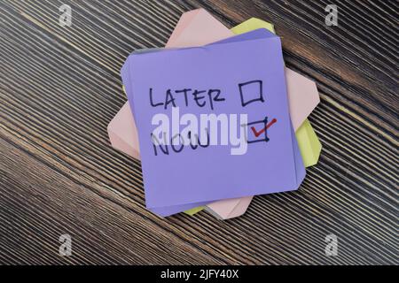 Concept of do it now or later write on sticky notes isolated on Wooden Table. Stock Photo