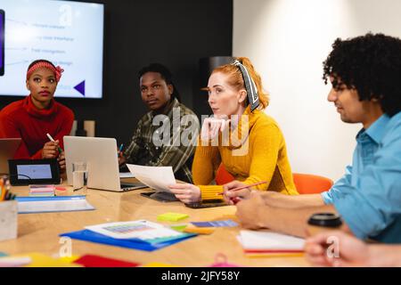 Serious female caucasian app developer with colleagues in board room at office Stock Photo