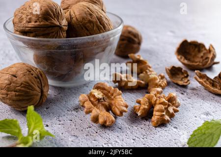 Selective focus on walnuts in a bowl and kernels on white background Stock Photo