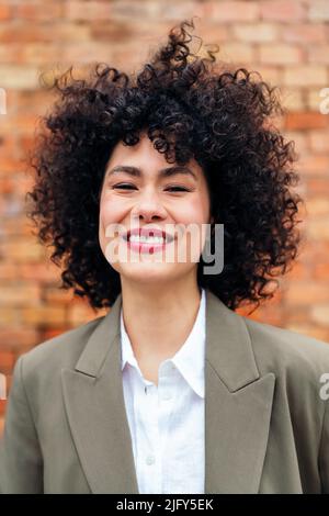 portrait of a young woman with curly hair smiling Stock Photo
