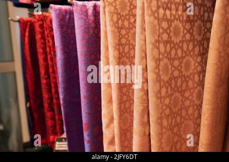 Several colorful and stylish scarves on a hanger. Fabric and handkerchief for sale in shop Stock Photo