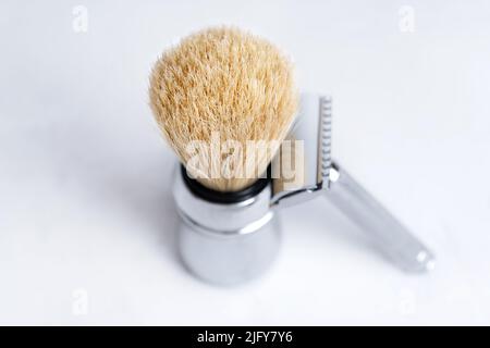 Chrome-plated safety razor and shaving brush isolated on light gray background. Stock Photo