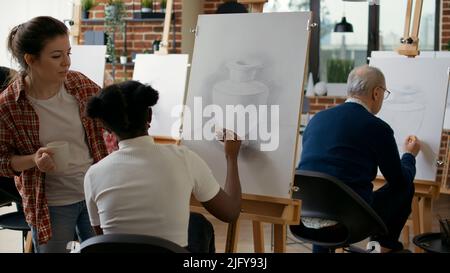 Young artist explaining drawing technique to elder person, using pencil ...