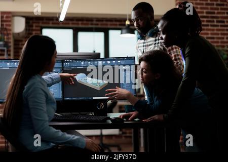 Digital engineering experts collaborating in order to develop advanced scene. Production department team gathered around 3D artist engineer trying to solve geometry problem. Stock Photo