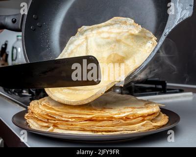 https://l450v.alamy.com/450v/2jfy9fr/human-hands-holding-a-spatula-and-a-frying-pan-spread-hot-pancake-on-the-dish-from-which-steam-comes-home-kitchen-traditional-treat-for-the-holiday-of-maslenitsa-2jfy9fr.jpg