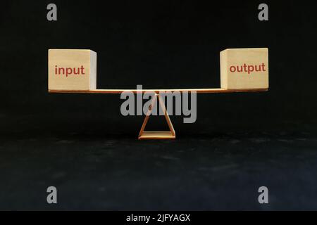 Input equals output balance and process efficiency and productivity concept. Seesaw in dark black background. Stock Photo
