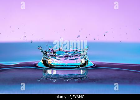 Water splash isolated on violet color background. Stock Photo
