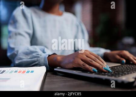 Close up shot of hedge fund company trader sitting at desk in office while using laptop to analyze live market charts. Financial analyst sitting in workspace while reviewing real time trend data. Stock Photo