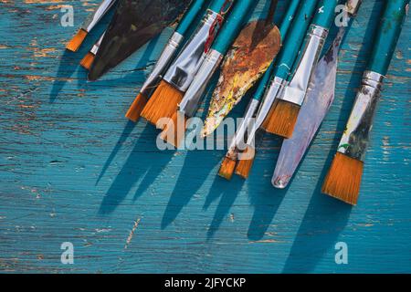 Artistic art supply utensils with paintbrushes on turquoise wooden background with copy space. Stock Photo