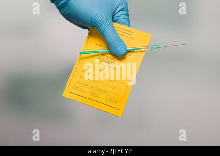 doctor's hand with document of international certificates of vaccination and a syringe Stock Photo
