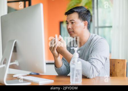 Asian man using hand sanitizer gel to clean his hand, Work from home and Healthy concept Stock Photo