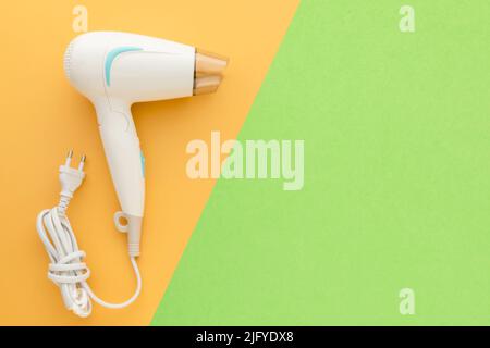 Top view new white hair dryer with cable on pink background with copy space for text or design Stock Photo