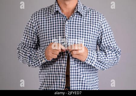 Close up man buttoning shirt studio shot on grey background Stock Photo