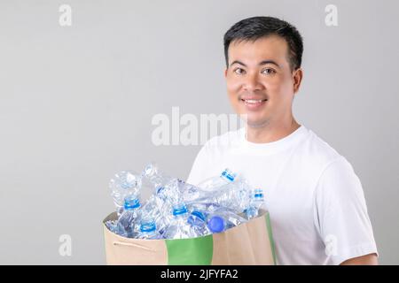 Recycle concept : Portrait Asian man holding many empty clear old water bottle. Studio shot on grey background Stock Photo