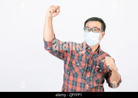 Passed bad situation concept : Asian man wearing protective face mask in action of glad, victory or very happy isolated on grey background Stock Photo